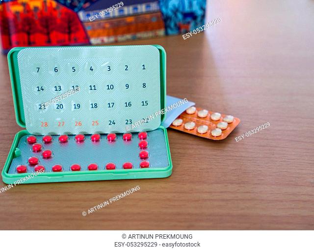 Contraceptive pills with modern packaging on the brown wood work table beside notebook. Birth control pills in blister pack. Family planning