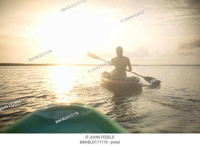 Caucasian woman rowing canoe on still lake