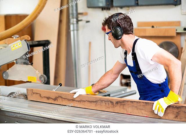 worker in a carpenter's workshop using saw machine