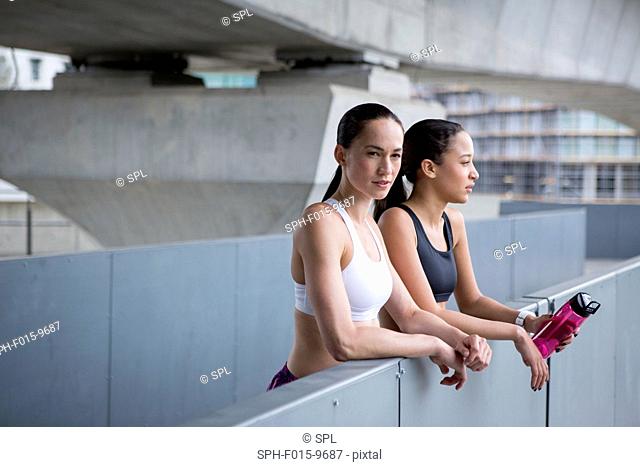 MODEL RELEASED. Two young women in sports clothing resting
