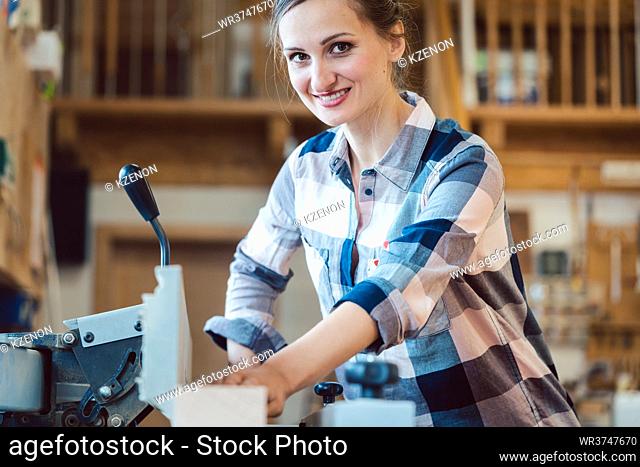 Closeup of carpenter woman at circular cutter working on a wooden plank