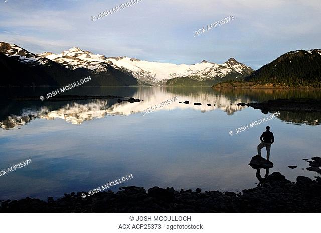 A hiker is silhouetted by the Sphinx Glacier and Garibaldi Lake in Garibaldi Provincial Park near Whistler BC