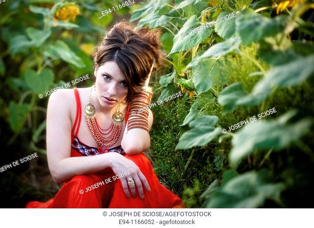 26 year old brunette woman wearing a red dress in a field of sunflowers
