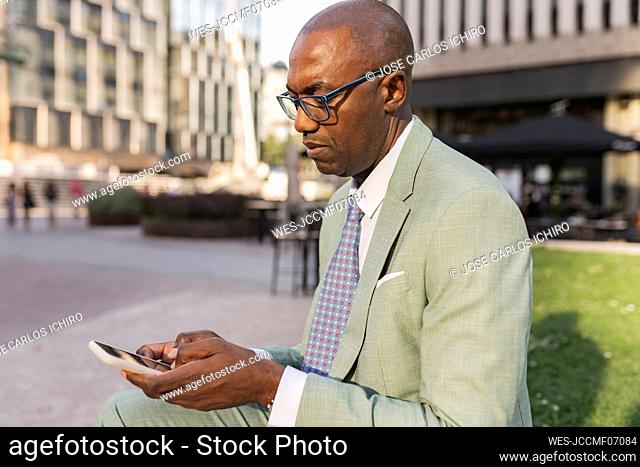 Mature businessman using mobile phone sitting at financial district