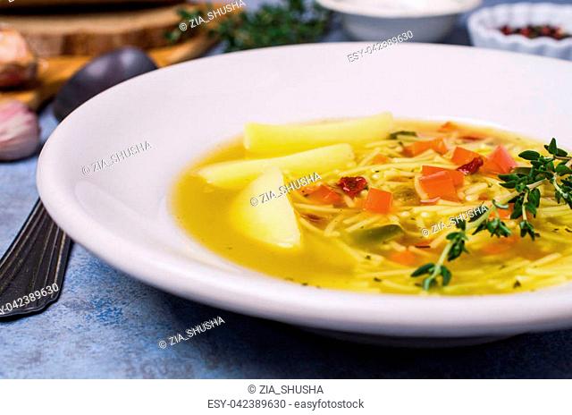 Soup with pasta and vegetables in bowl on stone background. Selective focus
