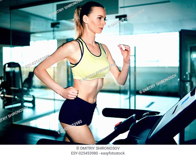 Active female running on treadmill in gym