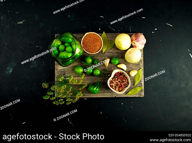 VEGETABLES TOMATOES AND SPICES ON THE BOARD. ONIONS GARLIC TOMATOES DILL SPICES ON GREY WOODEN BOARD ON A RAISED STONE SURFACE. THE CONCEPT OF SALTING