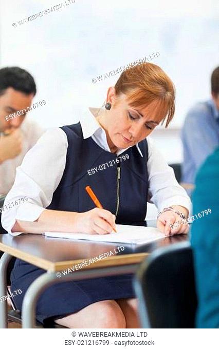 Concentrated female mature student sitting in classroom