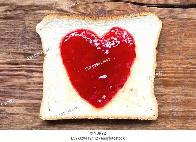 fried toast with red jam in shape oh heart on vintage wood