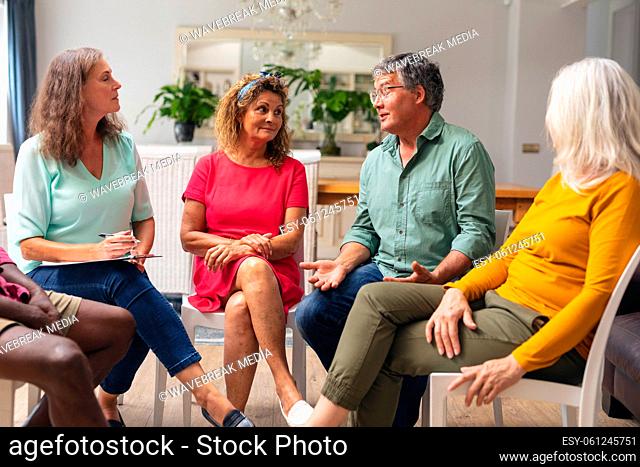 Caucasian senior man discussing with multiracial people during group therapy session
