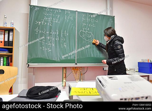 School lessons in times of the coronavirus pandemic. A teacher stands with face mask, mask on the blackboard. Since the windows are open