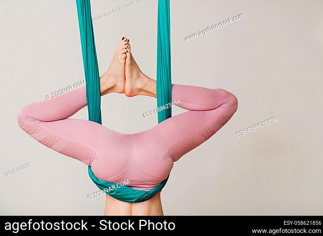 Aerial antigravity yoga concept. Woman practicing fly yoga in anti-gravity yoga studio using green hammock