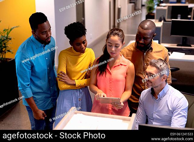 Hispanic businesswoman discussing over tablet pc with biracial colleagues at modern workplace