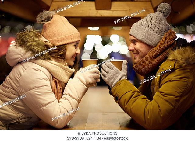 happy young couple with coffee at christmas market