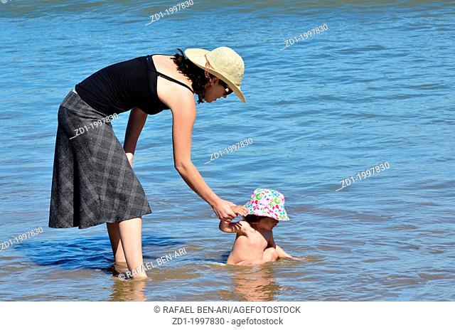 A mother play with here baby child at sea during summer vacation