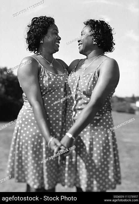 Portrait of women twins holding hands