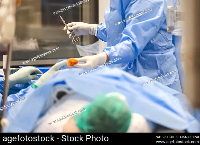 PRODUCTION - 29 November 2023, Schleswig-Holstein, Rendsburg: A surgical nurse (r) hands the surgeon a swab during an operation in the Schön Klinik's operating...
