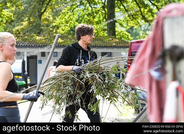 25 August 2023, Bavaria, Lindau: A man and a woman remove branches from a campsite. The previous night, a severe thunderstorm had moved across the Southwest