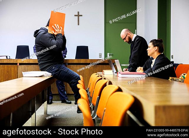 05 October 2023, Bavaria, Munich: The defendant (l) sits on a table in front of his lawyers Francesca Rossiello-Bianco (r) and Deniz Aydin (2nd from right) in a...