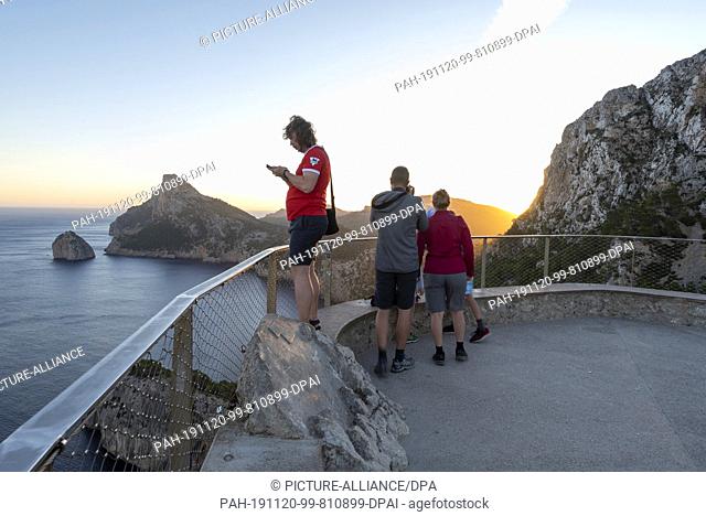 09 October 2019, Spain, Cap De Formentor: A family observes the sunrise at Cap de Formentor at the Mirador des Colomers vantage point