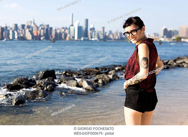 USA, New York City, portrait of young woman in front of Manhattan skyline
