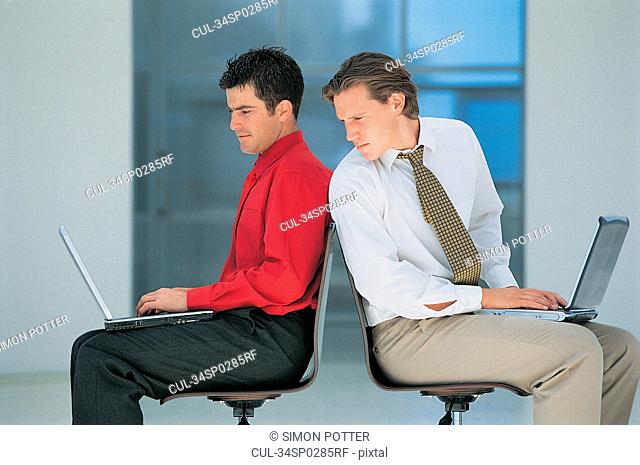 Businessmen using laptops in office