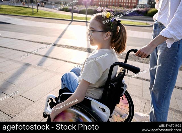 Woman with girl in wheelchair at park on sunny day