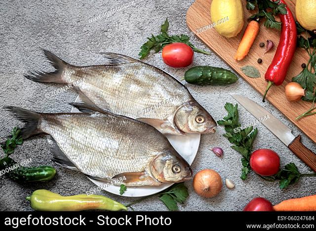 On the plate are two large bream. Nearby are vegetables and spices for cooking this river fish. Top view with copy space. Flat lay