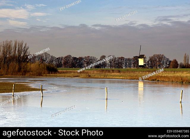 Frozen river foreland from the river Maas near the Dutch village Batenburg with the windmill in the background
