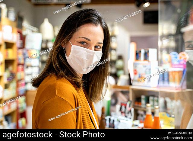 Young woman wearing protective face mask standing in grocery store during pandemic