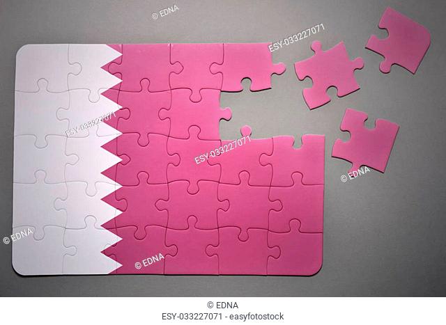broken puzzle with the national flag of qatar on a gray background