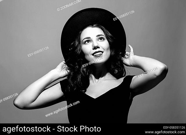 Profile portrait of a beautiful elegant brunette lady woman with long hair wearing a black hat and looks up. Black and white