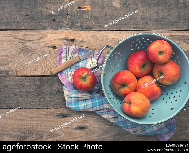 Delicious organic apples in an old used colander on a rustic wooden table, flat tone vintage style with view from above
