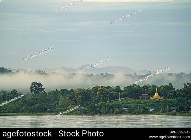 Dawn morning mist rising over a village stupa on the jungle covered banks of the Ayeyarwady (Irrawaddy) River; Rural Jungle, Kachin, Myanmar (Burma)