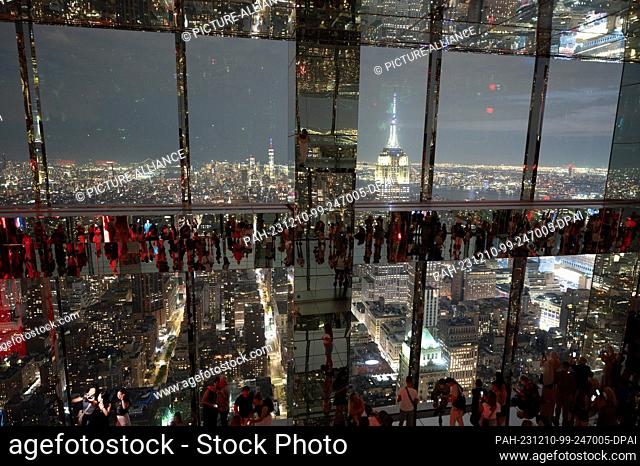 04 September 2023, USA, New York: Visitors stand in front of the Manhattan skyline after sunset on the glazed viewing platform The Summit at One Vanderbilt