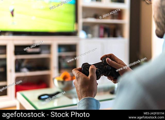 Young male gamer playing video game at home