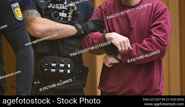 07 December 2023, Baden-Württemberg, Stuttgart: The defendant (r) is led into the courtroom at the start of a trial for fifteen counts of attempted murder