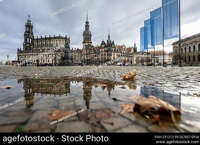 12 December 2023, Saxony, Dresden: The Hofkirche (l-r), the Hausmannsturm and the Residenzschloss are reflected in a puddle on Theaterplatz