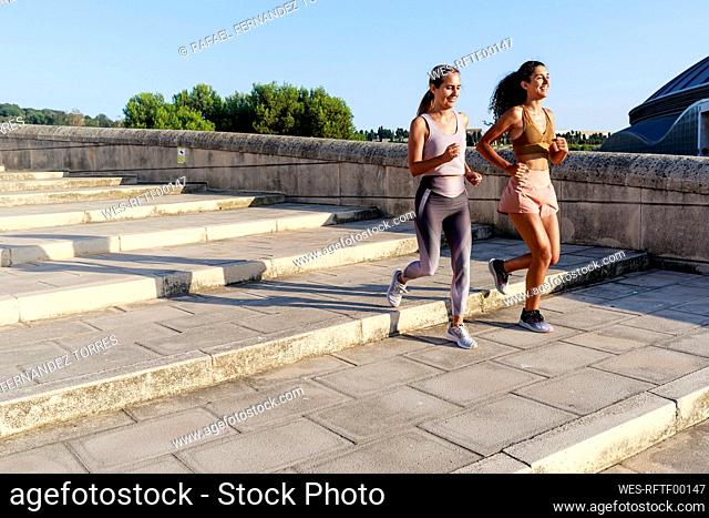 Smiling mother and daughter running on stairs