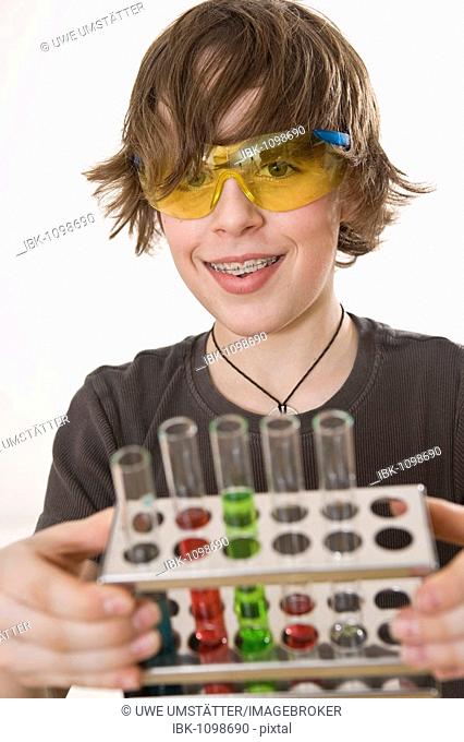 Boy wearing safety glasses, holding a stand with test tubes