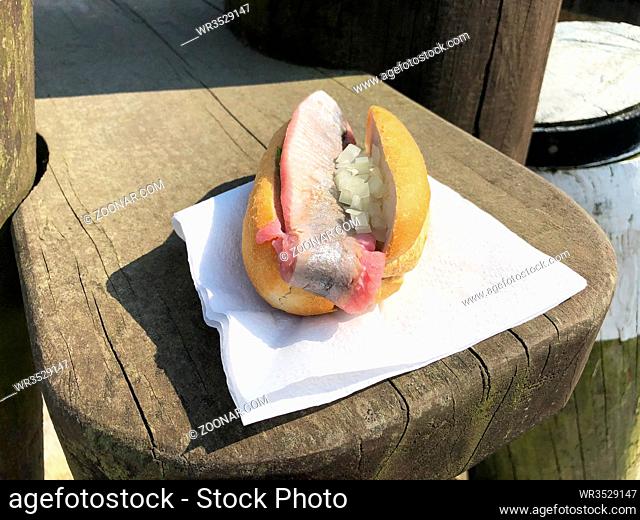 young herring or matie german-style fish sandwich with raw onion in bread roll