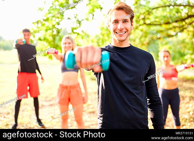 Junge Leute beim Hanteltraining mit Kurzhanteln für Muskelaufbau in der Natur