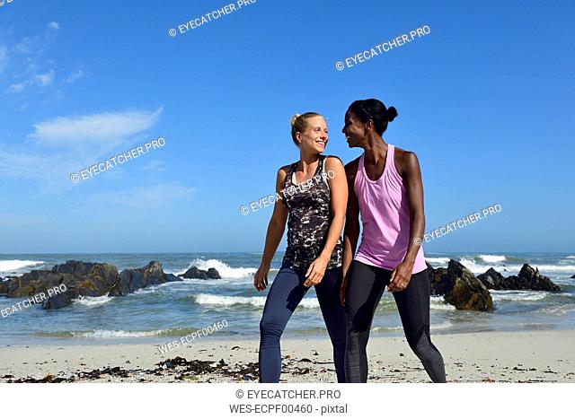 Two happy women walking on the beach