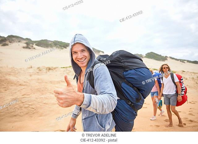 Portrait confident man with paragliding parachute backpack on beach