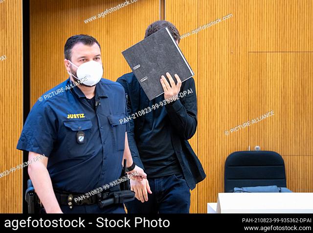 23 August 2021, Bavaria, Munich: One of two men charged with murder (r) is led into the courtroom before the trial begins
