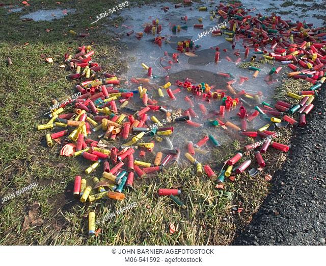 Spent shotgun shells and pieces of clay pigeons lay on the ground at a shooting range in the United States