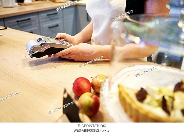 Waitress holding card reader at counter in a cafe