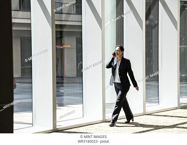 Businesswoman on the phone and walking through the lobby of a large business centre