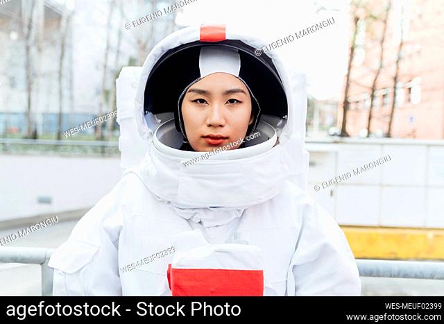 Serious female astronaut wearing space suit in city