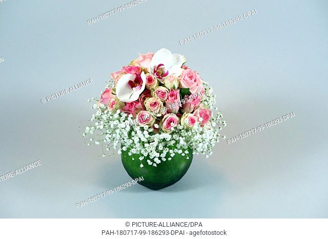 14 March 2018,  Germany, Berlin: A colourful bouquet of flowers with pink roses, white moth orchids, white gypsophila in a green vase
